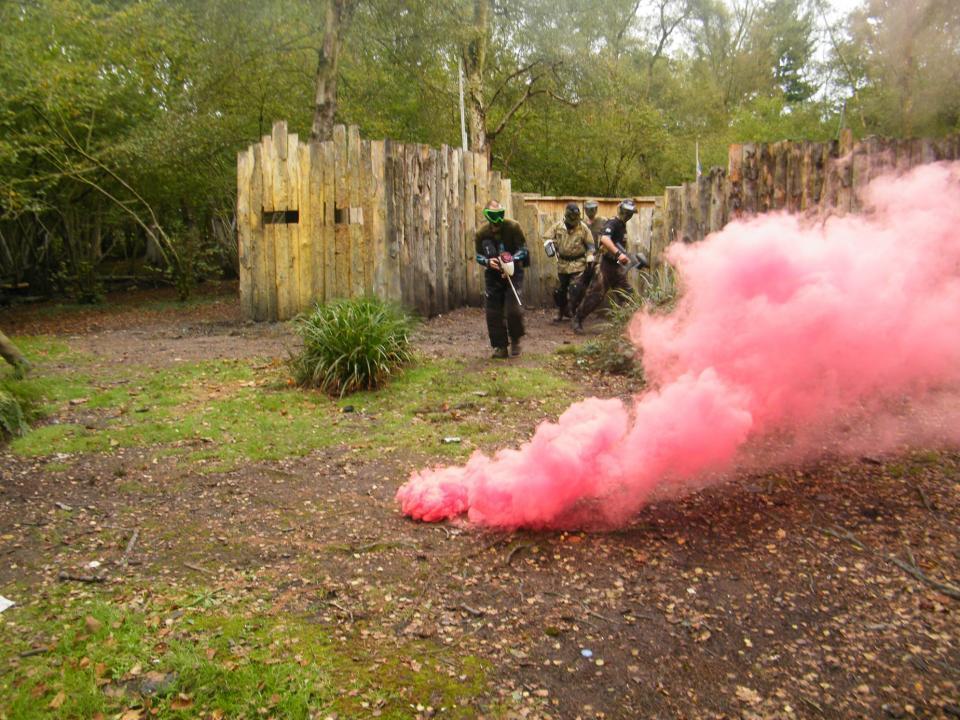 People paintballing with red smoke in foreground