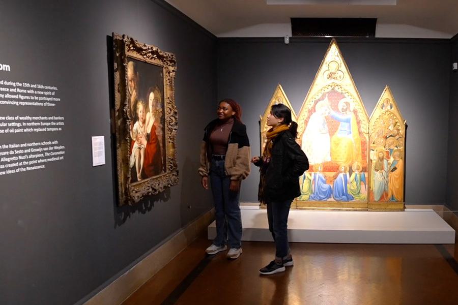 Two people looking at a painting inside an art gallery