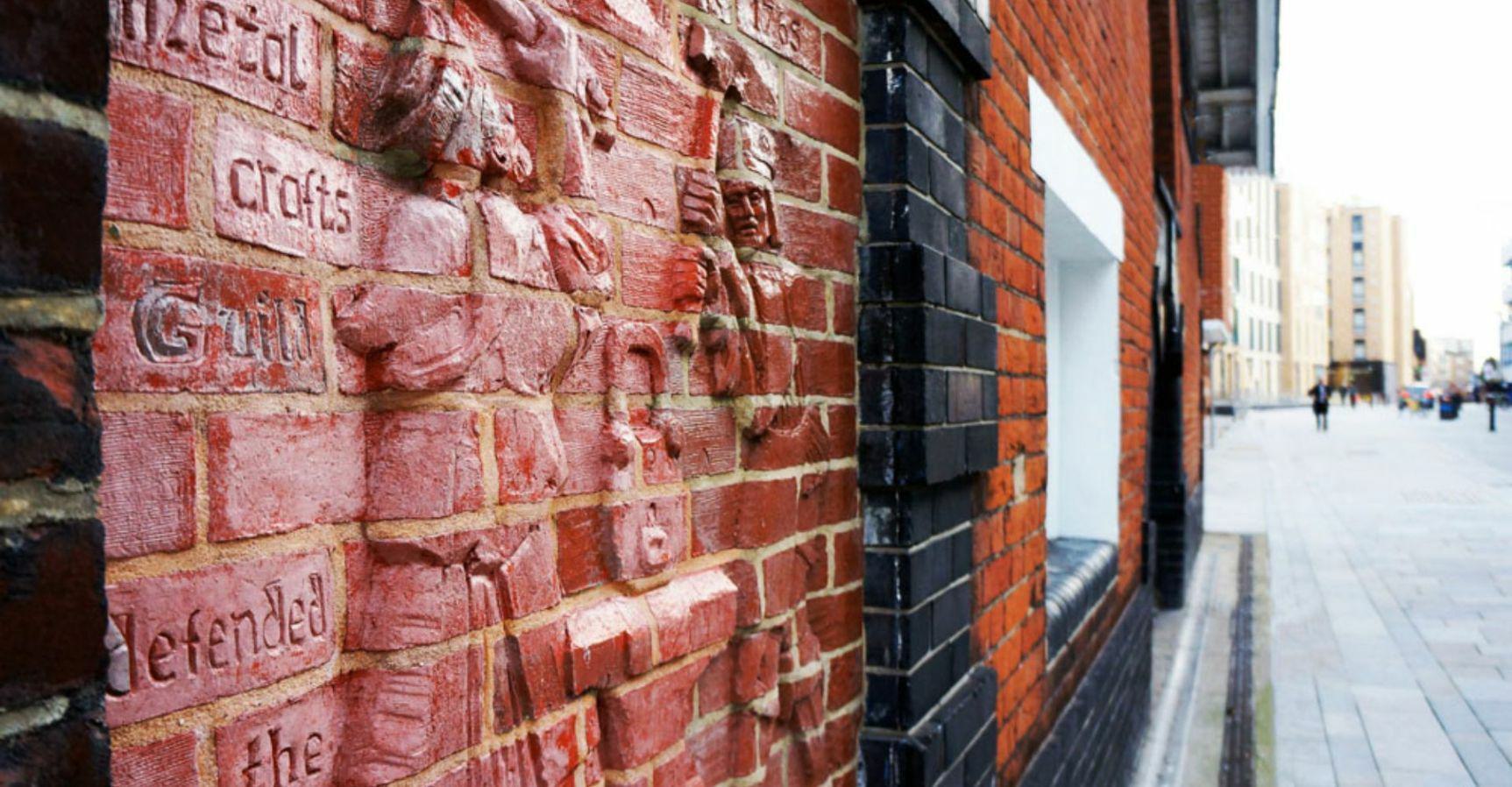 Defenders of the East Gate sculpture on a brick wall