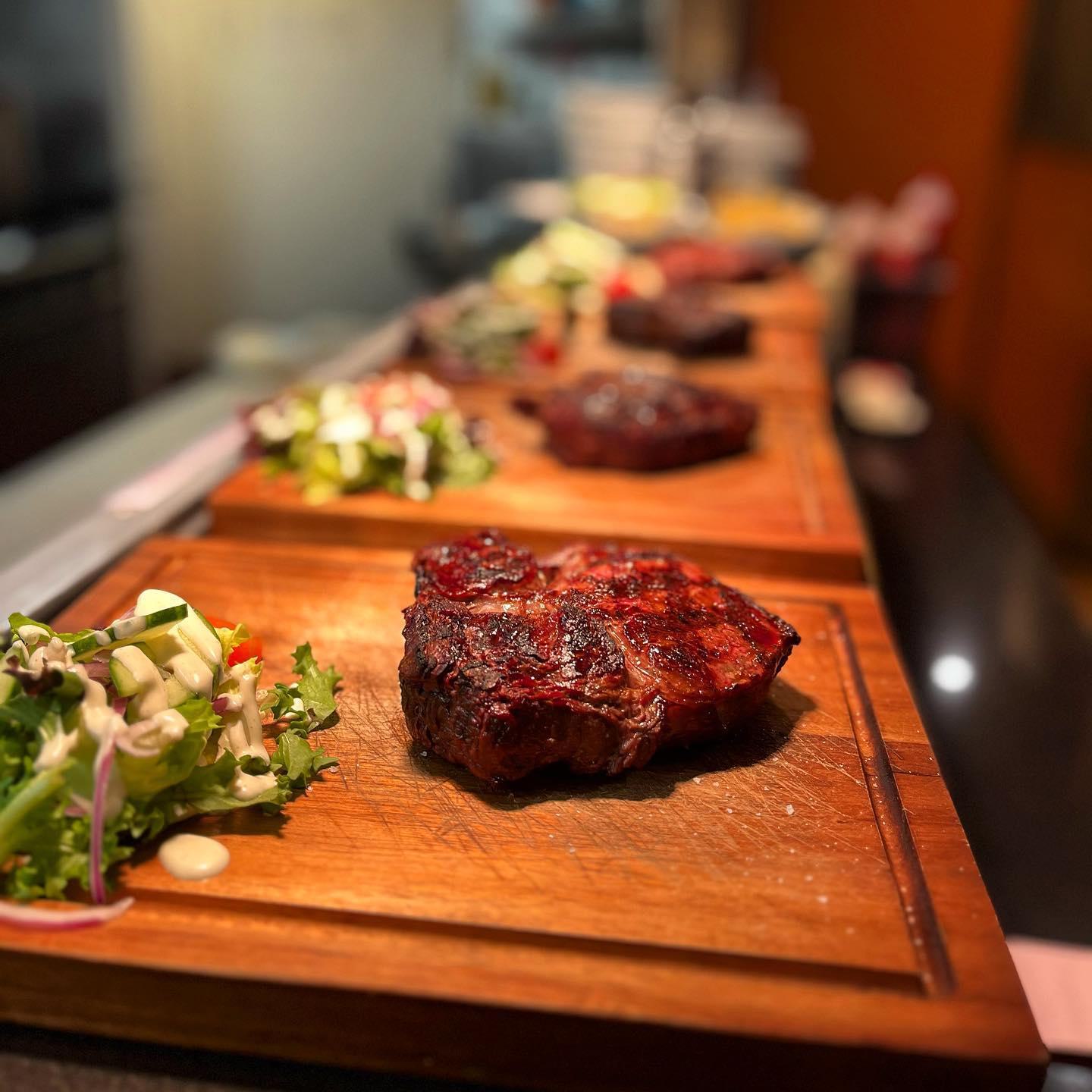 Freshly grilled steak on wooden chopping board with side salad at Argento