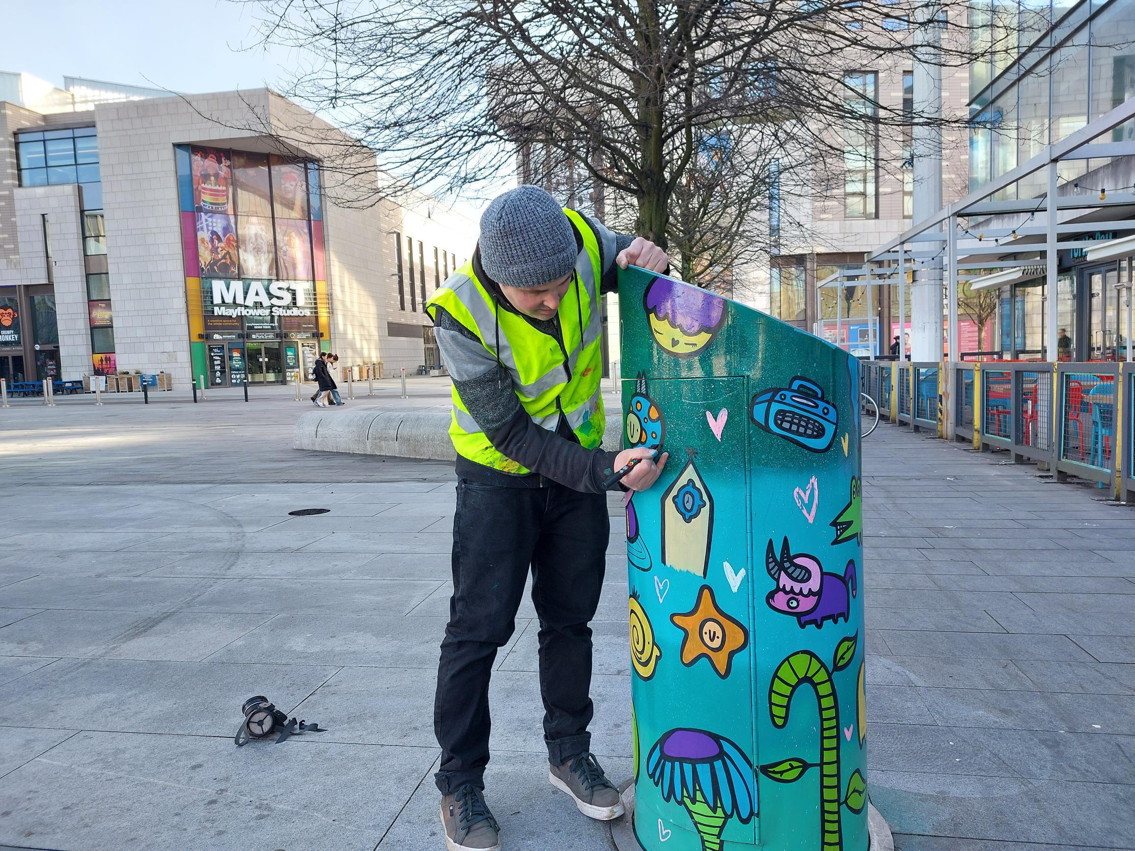 Local Artist Kev Munday painting design on utility bin in Southamptons Cultural Quarter