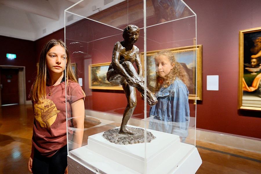Two young girls looking at a sculpture inside an art gallery