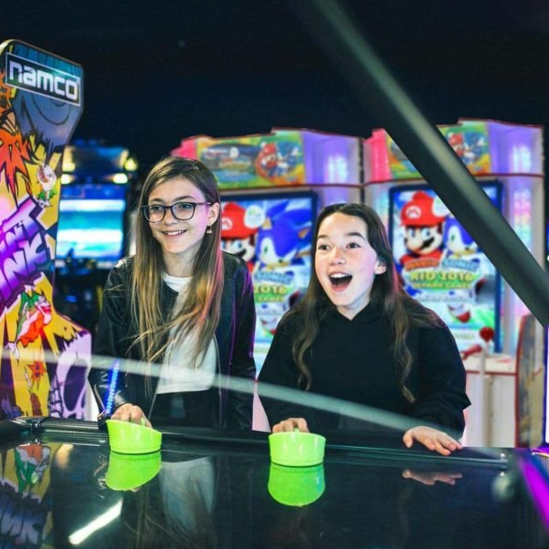 Two young girls playing air hockey at High Score Arcade