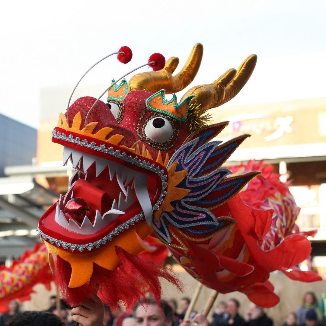 Red dragon held up on sticks by people walking in a parade