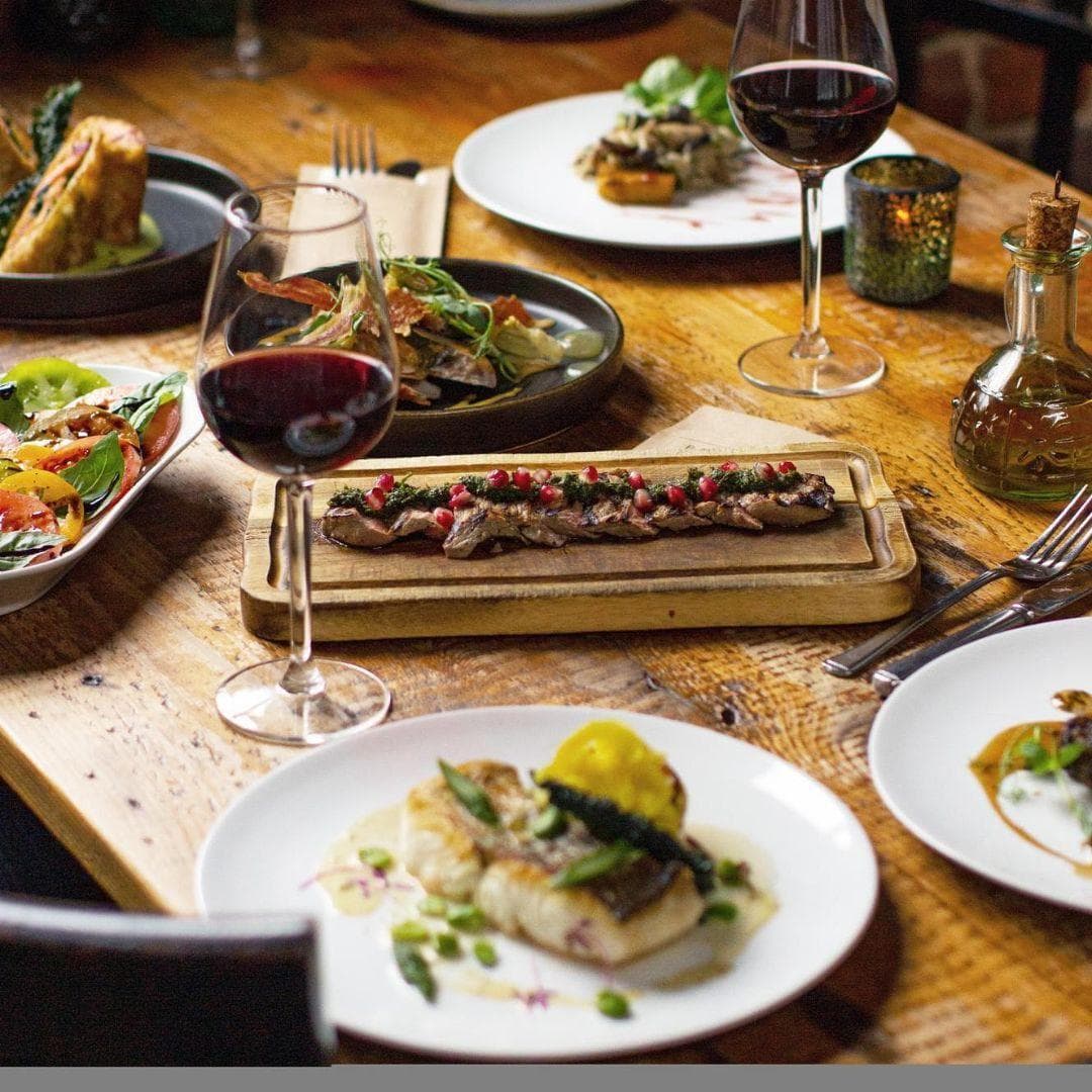 Rustic assortment of colourful seafood dishes next to a glass of red wine from Bacaro