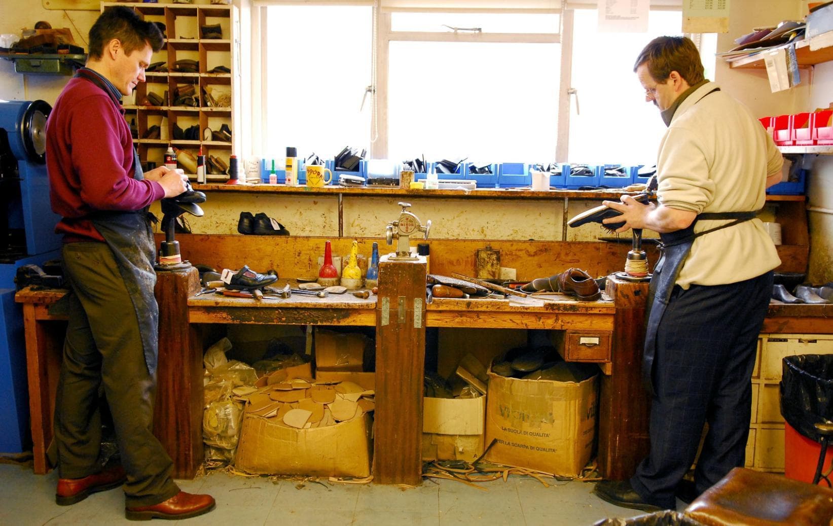 Two male shoe cobblers working on shoes in WJ French and Son workshop